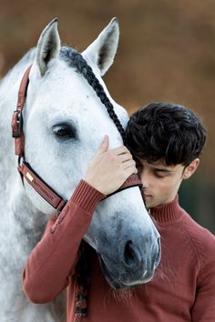 a young man is hugging his horse's bridle