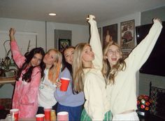 a group of young women standing next to each other in front of a tv holding cups