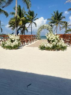 an outdoor wedding setup on the beach with white flowers and greenery in the foreground