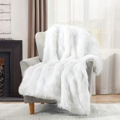 a white fur blanket sitting on top of a chair in front of a fire place