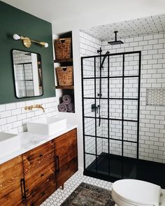 a white toilet sitting next to a walk in shower under a bathroom mirror above a sink