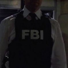 a man in a suit and tie wearing a fbi vest