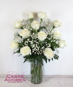 a vase filled with white roses and baby's breath