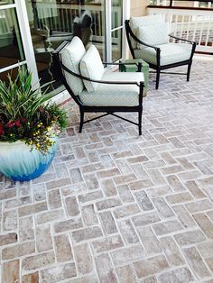 two chairs and a table sitting on a patio next to a building with glass doors