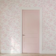 an empty room with a pink door and floral wallpaper