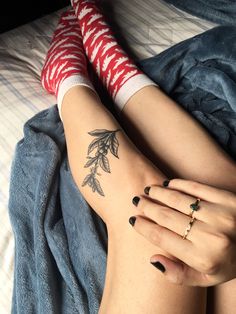 a woman laying on top of a bed with her legs crossed and tattoos on her arm