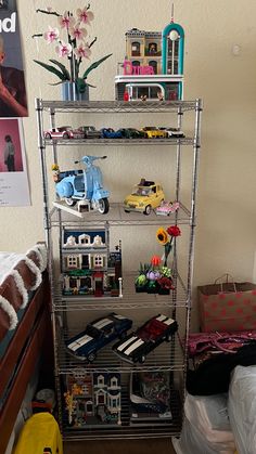 a metal shelf filled with lots of toy cars next to a bed in a bedroom