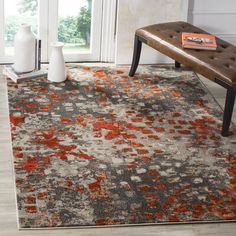 an orange and gray area rug in a living room with white vases on the floor