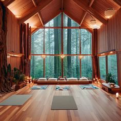 a yoga room with wooden floors and large windows overlooking the woods in front of it