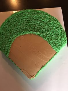 a cake with green frosting on top of a white sheet paper covered in grass