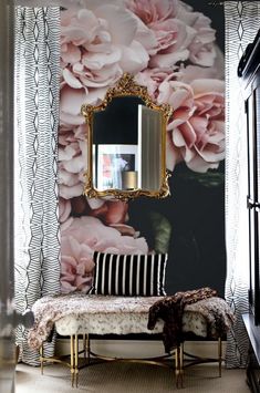 a room with flowers on the wall and a bench in front of it next to a mirror