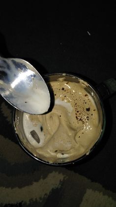 a spoon with some food in it on top of a black table and camouflage cloth