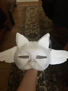 a person is holding a paper mask that looks like a cat