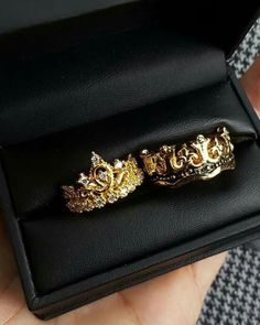 two gold rings sitting on top of a black box in someone's hand,