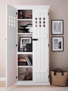 a white bookcase in the corner of a room with pictures on the wall behind it