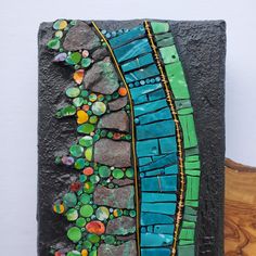 a piece of art made out of rocks and colored glass beads on top of it