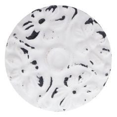 a white plate with black spots on the top and bottom, sitting in front of a white background