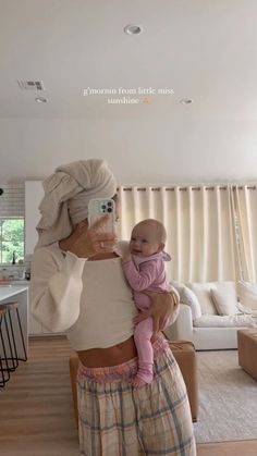 a woman holding a baby in her arms and taking a selfie with the phone