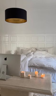 a laptop computer sitting on top of a white table next to a desk with candles in front of it