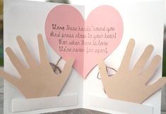 an open card with two hands and a heart shaped paper cutout on the inside