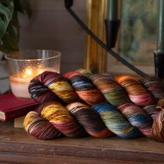 several skeins of yarn sitting on top of a table next to a candle