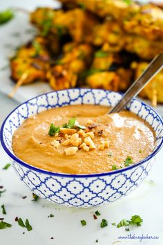 a blue and white bowl filled with soup next to some food on a plate in the background