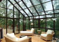 a living room filled with furniture and lots of glass walls on top of a wooden floor