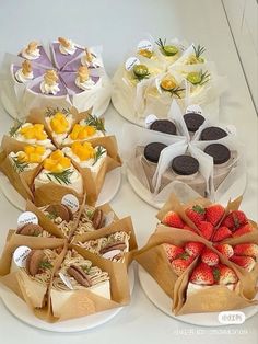 four different types of cakes and pastries on white plates with brown paper bags tied around them