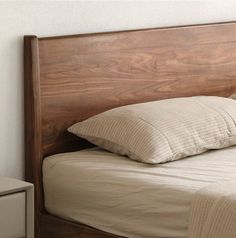 a wooden headboard with two pillows on it and a night stand next to it