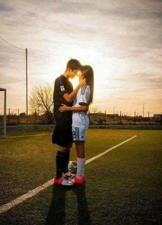 two people standing on top of a soccer field with the sun shining down behind them