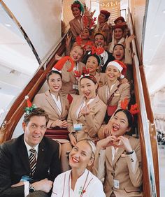 a group of women and men dressed in airline uniforms are posing on the steps of an airplane