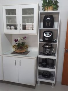 a kitchen with white cupboards and plants on the counter top next to an open door