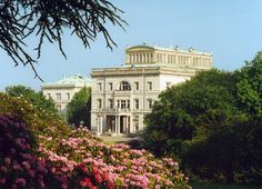 a large white building surrounded by trees and flowers