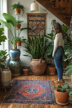 a woman is standing in front of plants and rugs on the floor next to stairs