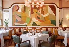 a dining room with tables and chairs in front of a large painting on the wall