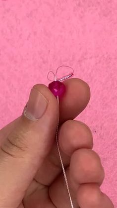 a person is holding a tiny red object in their left hand and the other hand has a string attached to it