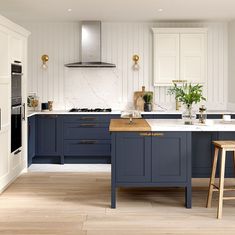 a kitchen with blue cabinets and wooden stools next to an island in the middle