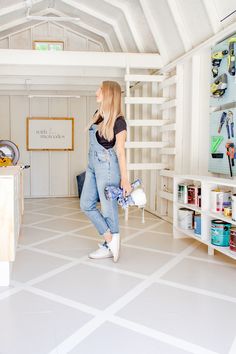 a woman in overalls and sneakers is standing in a room