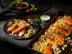 two pans filled with food on top of a black counter next to each other