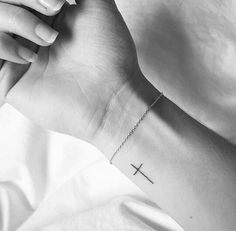 a person with a cross tattoo on their wrist