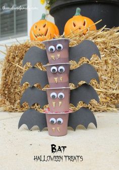 halloween decorations made out of toilet paper cups and bats on hay bales with pumpkins in the background