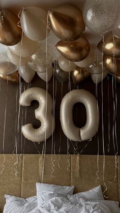 balloons and streamers hang from the ceiling above a bed