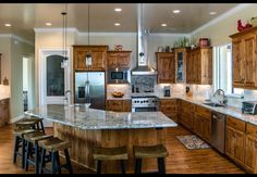 a large kitchen with wooden cabinets and stainless steel appliances, along with bar stools