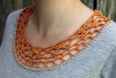 a woman wearing an orange crochet necklace