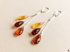 "Cherry, lemon and cognac colors amber earrings with silver for minimal jewelry admirers. Get these bright drop shape long amber earrings designed into a jewelry piece that catches every sight on the street! MATERIALS AND SIZE: Stone: 100% Natural Baltic Amber Other materials: silver 925 Weight: 5,2g (0,18 oz) Bead size: ~1,6 cm (0,62 in) x ~1 cm (0.39 in) Total earring length: ~8 cm (3,14 in) PLEASE NOTE: All our amber production is made of natural amber. Amber is an unique stone and every piec Modern Amber Drop Earrings, Modern Amber Earrings For Gift, Modern Amber Earrings As A Gift, Modern Yellow Teardrop Jewelry, Minimalist Amber Earrings For Gift, Amber Teardrop Earrings Gift, Amber Teardrop Earrings As A Gift, Baltic Amber Drop Jewelry In Amber Color, Baltic Amber Drop Jewelry In Amber