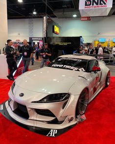 a toyota sports car is on display at an auto show, with people looking around