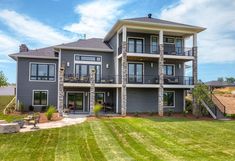 a large gray house sitting on top of a lush green field