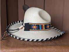 The Santa Fe Chief hat starts with a soft Gus palm hat body that has a 4" brim and 5" crown. Hand laced in 10mm wide black leather lace. The 2" wide beaded hatband has lots of colors in black, blue, red, yellow, orange and white. The back of the band has a deer antler bead for accent. Accented with an Indian Chief Concho and a guinea fowl feather. All hats are made to order. Allow up to 4 weeks for your hat to ship. Black Adjustable Panama Hat With Flat Crown, Traditional Wide Brim Fitted Hat, Traditional Fitted Wide Brim Hat, Western Style Black Panama Hat With Curved Brim, Black Western Panama Hat With Curved Brim, Southwestern Black Hat Bands For Country Events, Traditional Black Hat Bands For Festival, Adjustable Wide Brim Straw Hat For Races, Western Style High Crown Top Hat For Festival