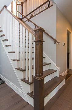 a white staircase with wooden handrails and wood flooring in a home's entryway