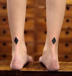 a woman's legs with black diamond tattoos on them